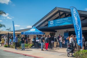 A picture of the outside of a church with people coming and going.