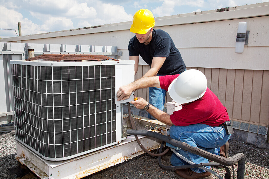 Two workers on the roof of a building working on the air conditi